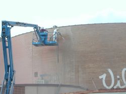 Two men on a crane remove the paint from the front of the Villa Theatre