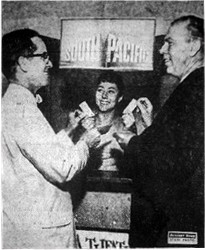 "LOOK WHO'S BUYING TICKETS! - Although they are donating the theater for 'South Pacific' premiere, John Denmen, left, city manager of Fox Wasatch Theaters, and Dick Frisbey, manager of the Villa Theater, purchase tickets for 'South Pacific' benefit premiere. Inez Hales is the cashier."